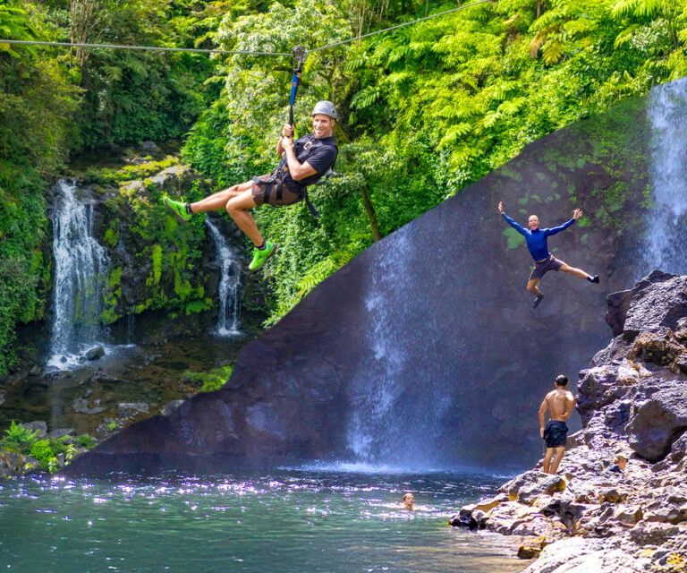 Guest at the base of a waterfall on the Zip & Dip combo tour
