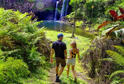 Couple hiking through lush Hawaiian jungle near a private waterfall